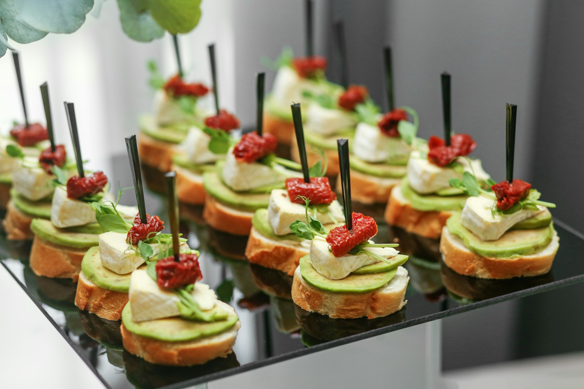 Festive decorated canapes for event with avocado and cheese and dried tomatoes. Eating at the event